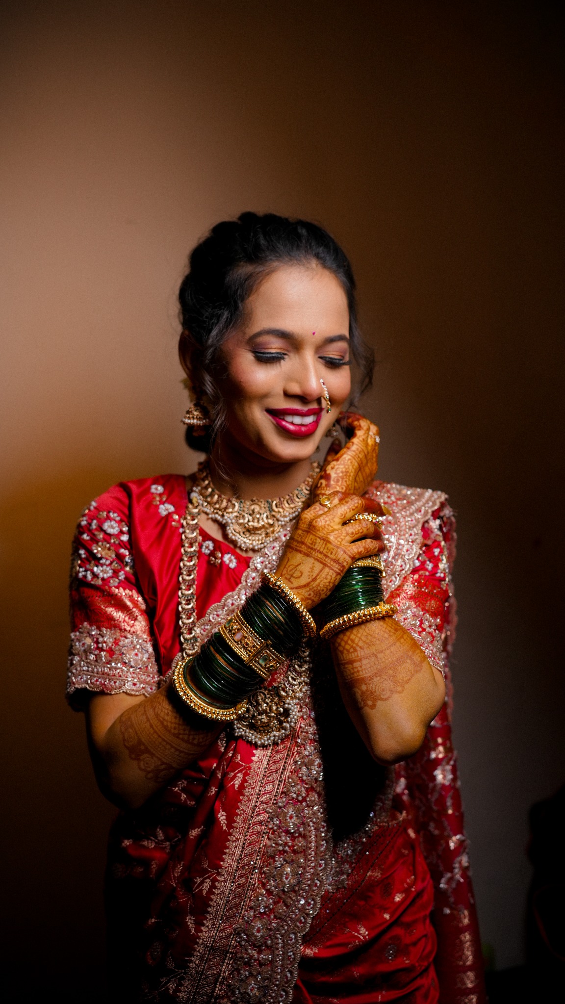 Bride holding her hands near her face, henna and bangles in view